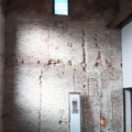 The wall is a brick construction covered in, now weathered, plaster. A window two floors up, a closed arch, vertical joints and various structural holes (for beams, the formwork etc) add to the complexity of the structure. 