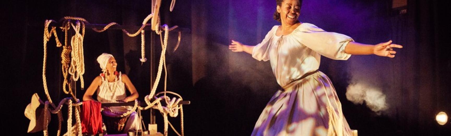 Production image from Sold - a woman dances alongside a drummer on a set strewn with ropes