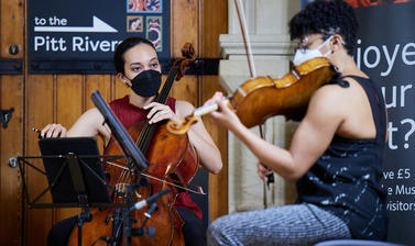 Two female musicians, playing violin and cello, captured in sat down position.