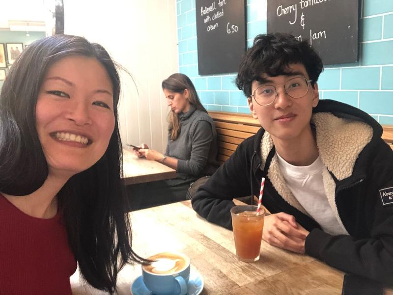 two people sitting in a cafe smiling at the camera