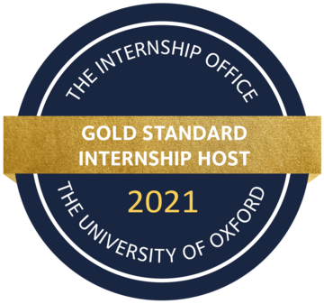 The badge consists of a blue circle with 'the Internship Office' and 'the university of Oxford' written in white letters. A ribbon in gold splits the circle horizontally, reading 'Gold Standard Internship Host' in white letters. 
