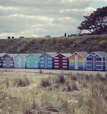 multicoloured beach sheds lined up on the beach