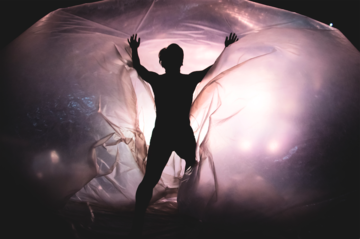 Backlit dancer heading into large transparent bubble