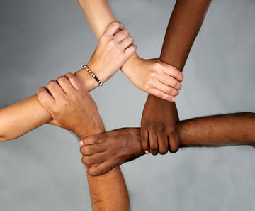 Five hands of different skin colour held together shaping a pentagon