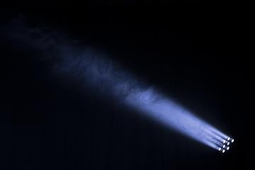 Spotlight cuts through smoke in dark theatre