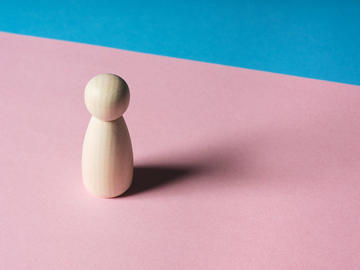 A pawn of a swedish wood standing on the pink section of a pink and blue board.