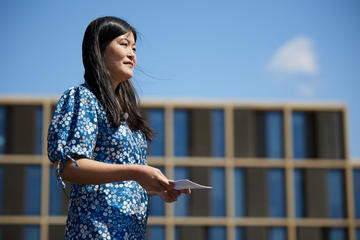 Close up of Jenny Wong wearing a blue dress and reading from a page on a sunny day in front of the Radcliffe Observatory