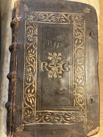 the cover of a small brown leather hardback book with raised bands on the spine. The cover features a gold tooled rectangular panel made with decorative rolls.