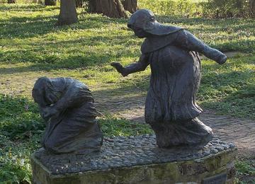 bronze statue of two religious sisters, one kneeling, one with a hand out standing
