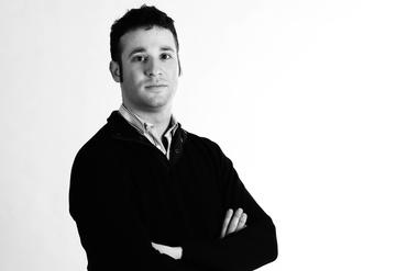 waist up shot of dark haired man in black jersey with arms crossed - black and white image, credit Lisa Wright