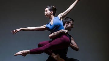 Image depicts a dynamic dancing pose where dancer Amy Thake is lifted by dancer Edd Mitton facing different directions.