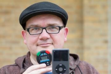 Image of Martyn Harry looking at the camera wearing a hat, glasses and holding video equipment