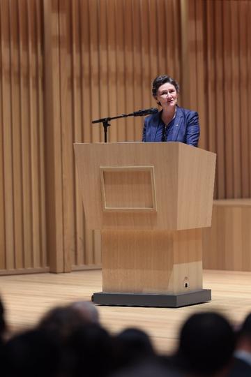 Woman standing behind lectern speaking into microphone