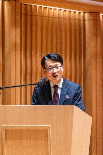 Man standing behind lectern speaking into microphone