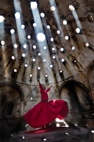 Person wearing a red gown dancing in an open cathedral. 