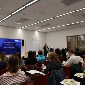 room of people looking at screen with one person presenting at front