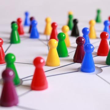 Board game play figures in different colours placed on a network of lines. 