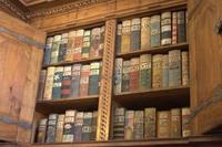 An open cabinet of old, colourful books.