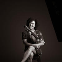 Black and white image of a woman sitting in a chair with a violin under her arm