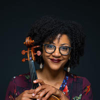 woman smiling in purple top holding a violin in front of her