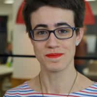 woman with short brown hair, black framed glasses and blue and white stripped top. Headshot