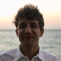 Man in white shirt smiling as the sun sets behind him