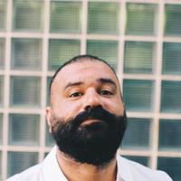 Khaled pride man looking at the camera in a open white shirt, face angled upwards