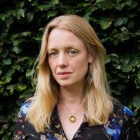 laura tunbridge in floral top, long blonde hair, standing in front of leaves