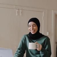 woman at a laptop holding a mug