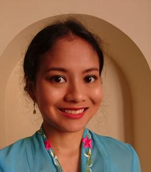 Hannah Nazri, they wear a blue top with pink flower details, dark hair tied up