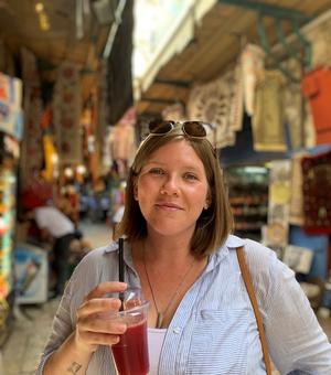 blond woman smiling at the camera holding a smoothie in a marketplace