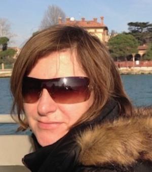 Gillian Lamb, wearing sunglasses and a coat, smiles at the camera