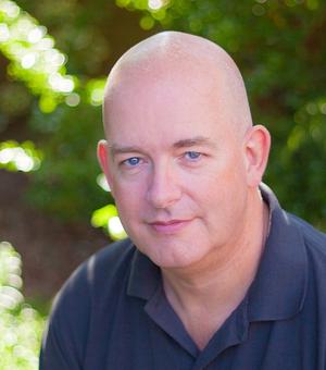 man in blue shirt sitting in front of out of focus trees