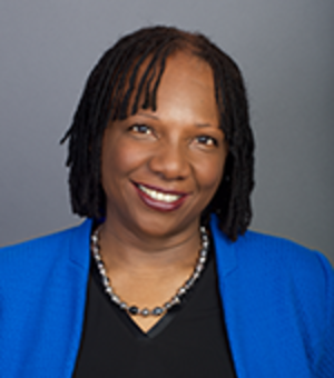 woman smiling at the camera, black shirt, blue jacket