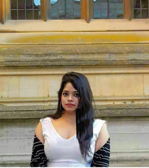 Ranjamrittika Bhowmik wearing white dress standing in front of building