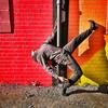 A dancer strikes a pose against a vivid red, orange and yellow wall